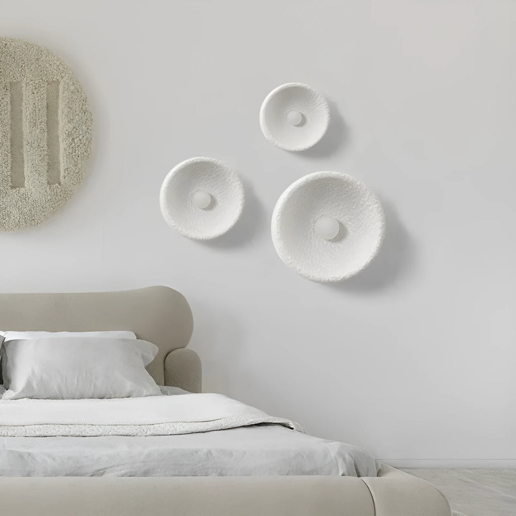 Japanese-style simple white resin wall lamp emitting warm light on a plain wall.