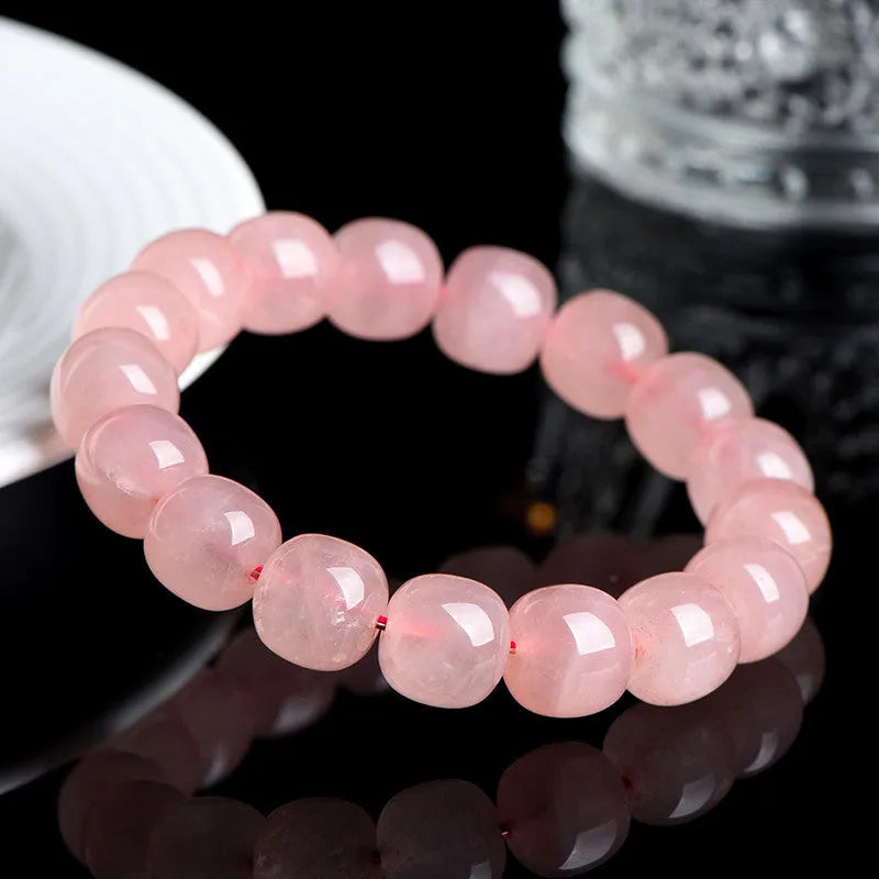 Natural pink crystal bracelet with 19 polished barrel-shaped beads on a wrist, showing geometric design.