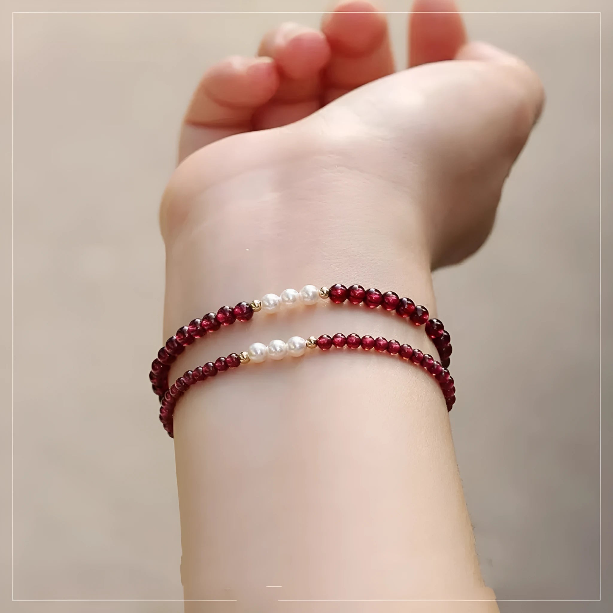 Close-up of a women's adjustable crystal bracelet with red garnet and white artificial pearl beads.