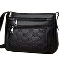 Women's black messenger bag with crossbody strap showing embossed detailing and exterior slit pocket