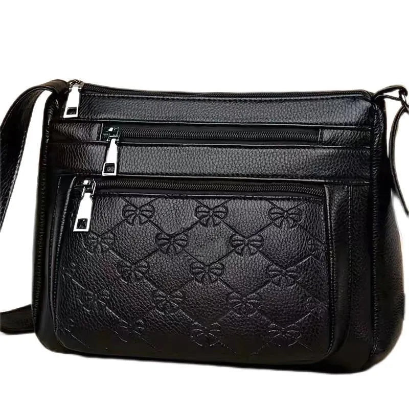 Women's black messenger bag with crossbody strap showing embossed detailing and exterior slit pocket