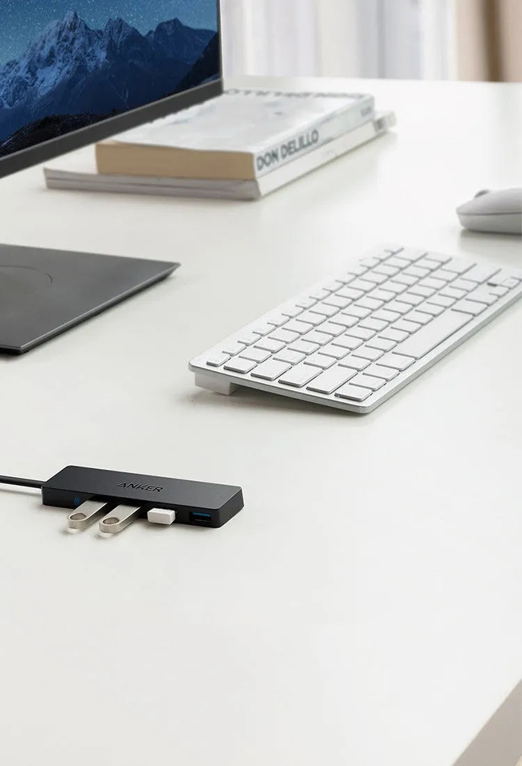 Black Anker USB 3.0 hub with four ports and a 20cm cable on a desk.