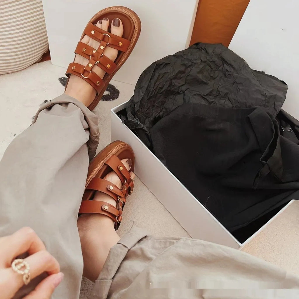 Women's white patent leather Roman sandal slippers with sheepskin upper on a wooden floor