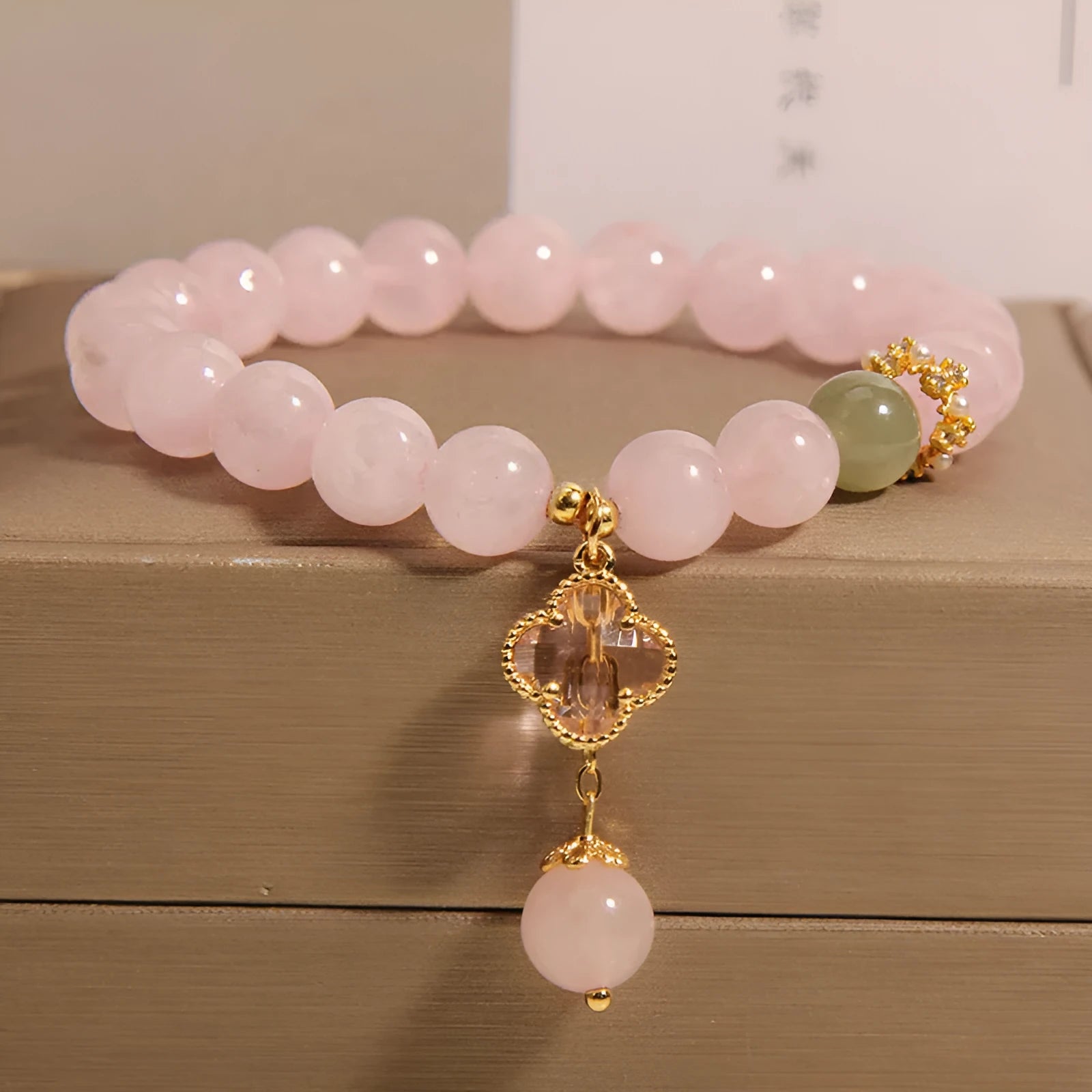 Pink crystal bracelet with four-leaf clover pendant and rhinestone details