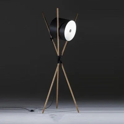 Modern three fork floor lamp with wood body and white acrylic shade on a wooden floor.