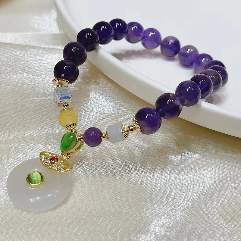 Purple amethyst bracelet with detailed money bag charm and peace buckle pendant on wrist