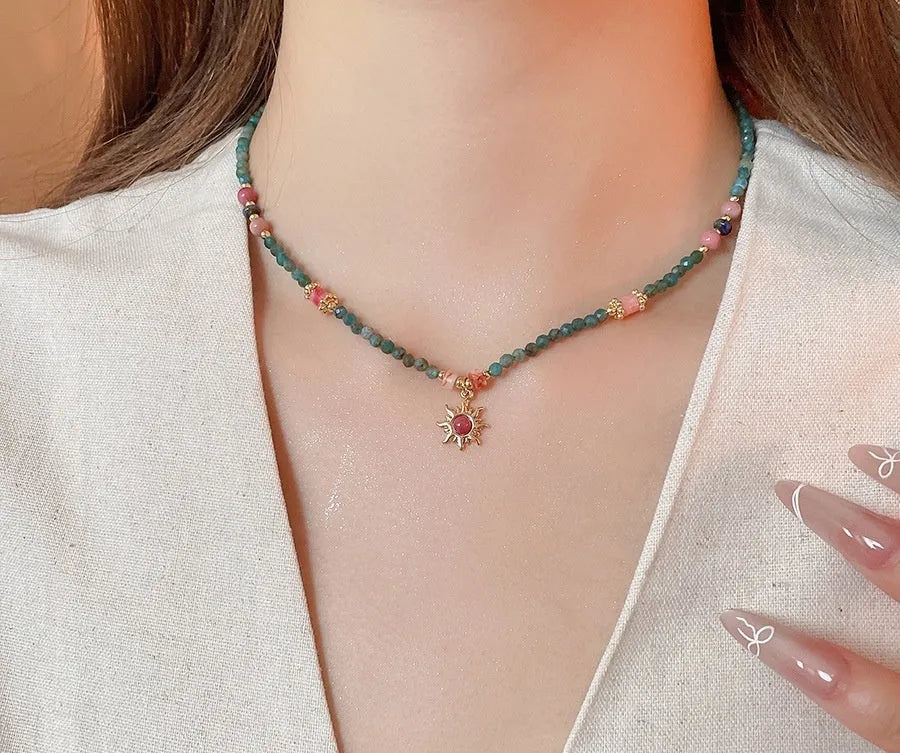 Freshwater pearl necklace with a blue stone sun pendant on a delicate clavicle chain.