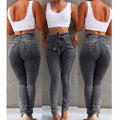 A pair of light blue fringed jeans with a distressed hem laid flat.