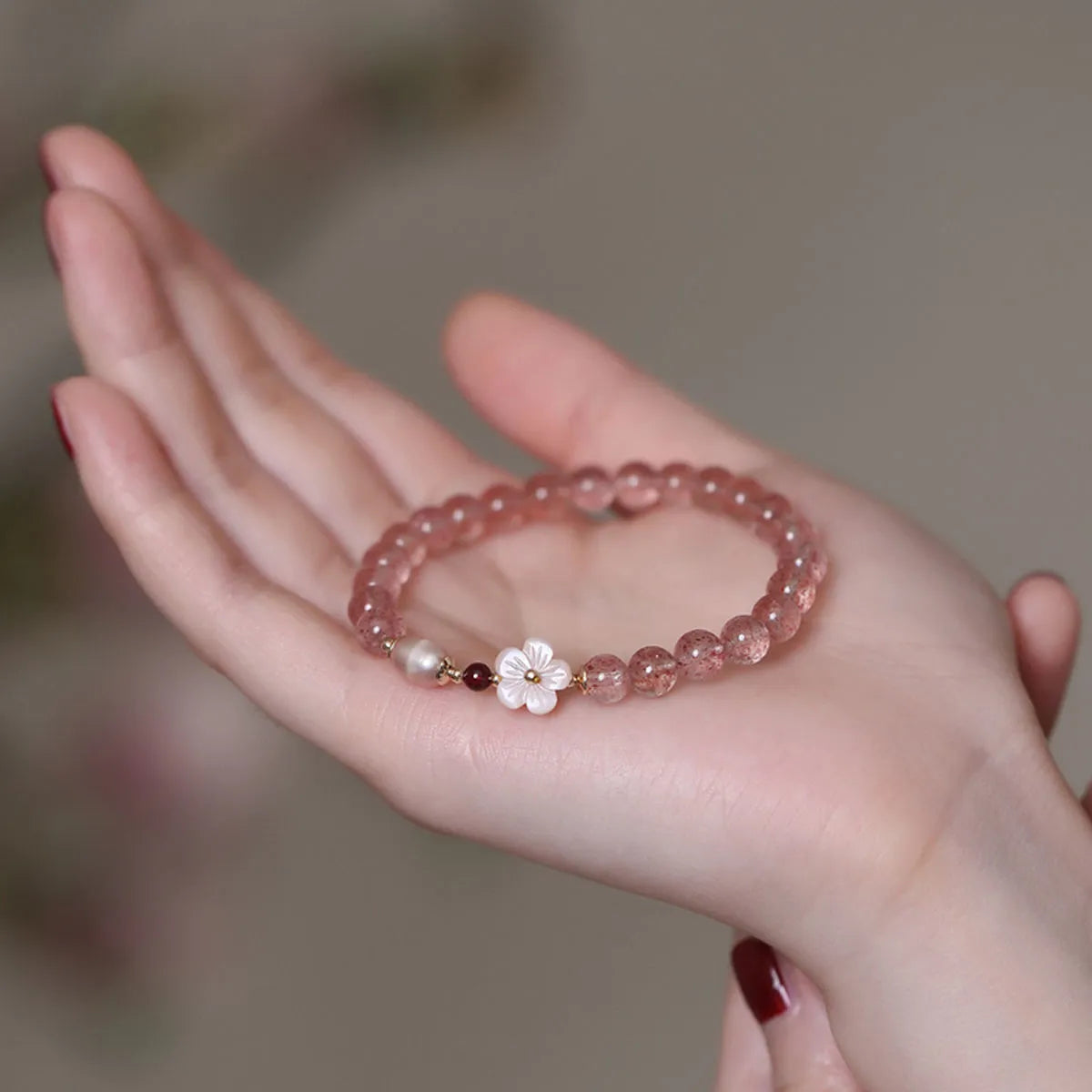 Strawberry quartz crystal bracelet with peach blossom floral design on wrist, showing adjustable 18-20cm length