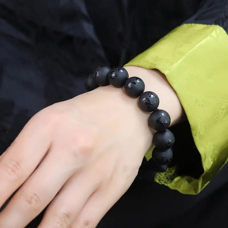 Natural frosted black agate bracelet with Sanskrit mantra and auspicious patterns, showing matte black stone glaze.