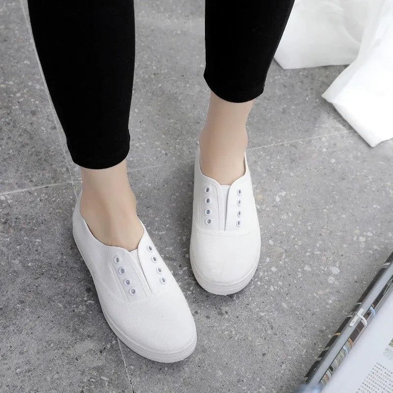 Low-top canvas sneakers in black, white, grey, and pink with a flat heel and cloth lining.