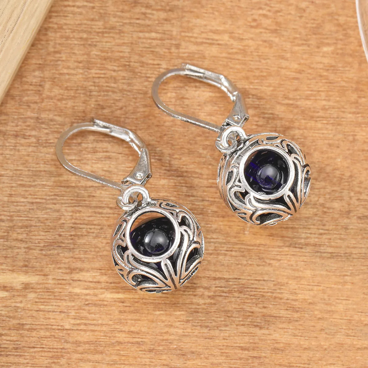Silver geometric pendant earrings with vintage engraving and hollow design around blue gemstone