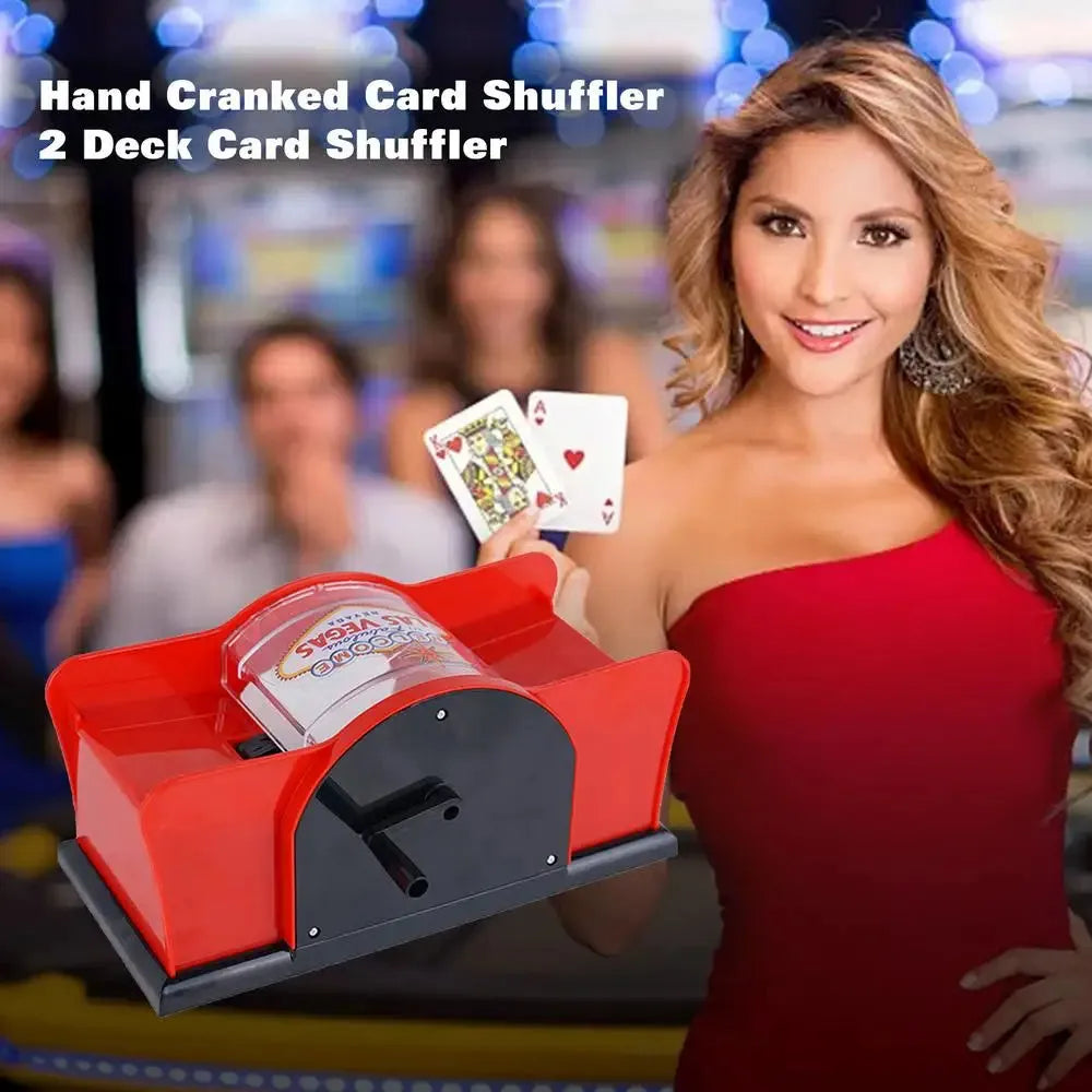 Black manual card shuffler with hand crank on a table next to playing cards.