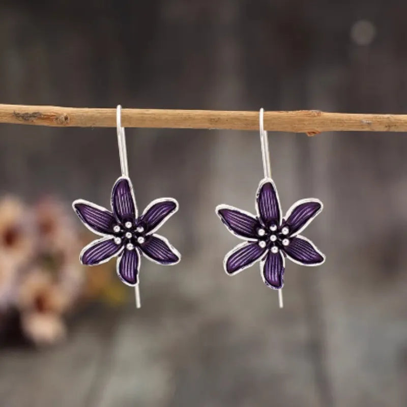 Purple flower-shaped alloy earrings with electroplated finish on white background