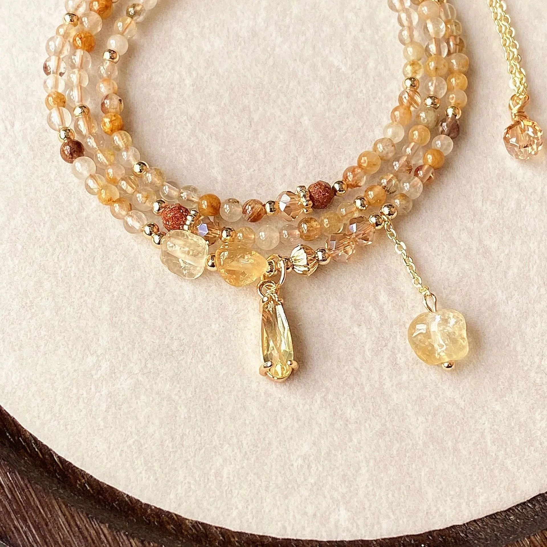 Gold three-circle layered bracelet with caramel citrine stones and a Saturn charm.