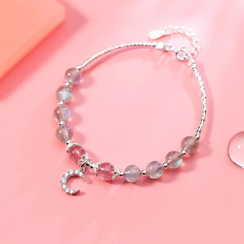 Handmade silver-tone adjustable bracelet with a moonstone bead and small crescent moon charm on a white background.