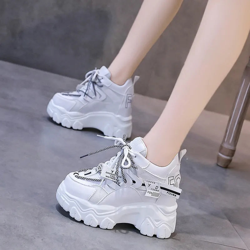 Women's white low-top platform sports shoes with cross strap and rubber sole on a light background