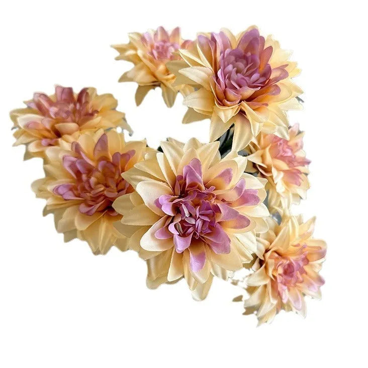 A fan-shaped display of silk dahlia, peony and rose flowers in a yellow colour on a wooden desktop.