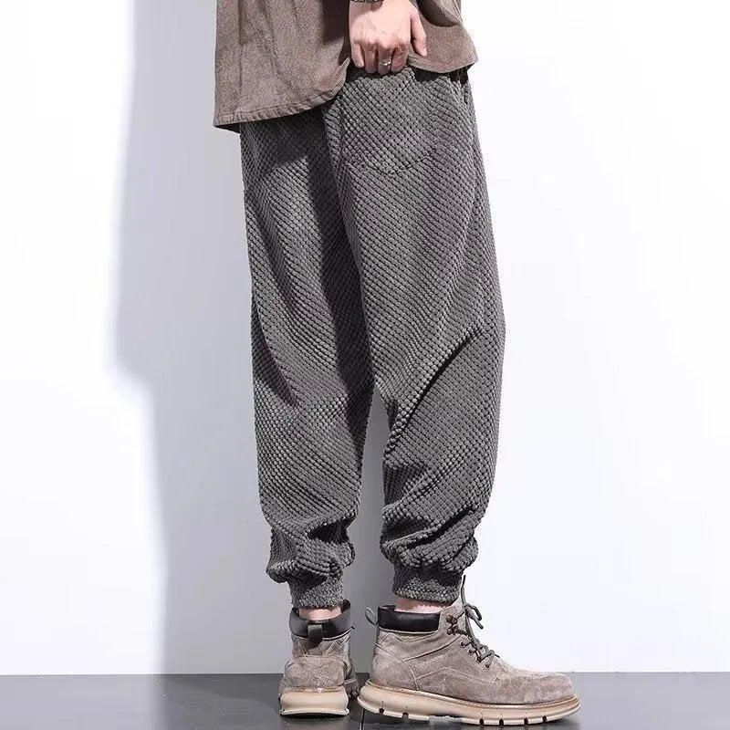 Man wearing grey ankle-tie sweatpants, showing the straight leg and adjustable cuff detail.