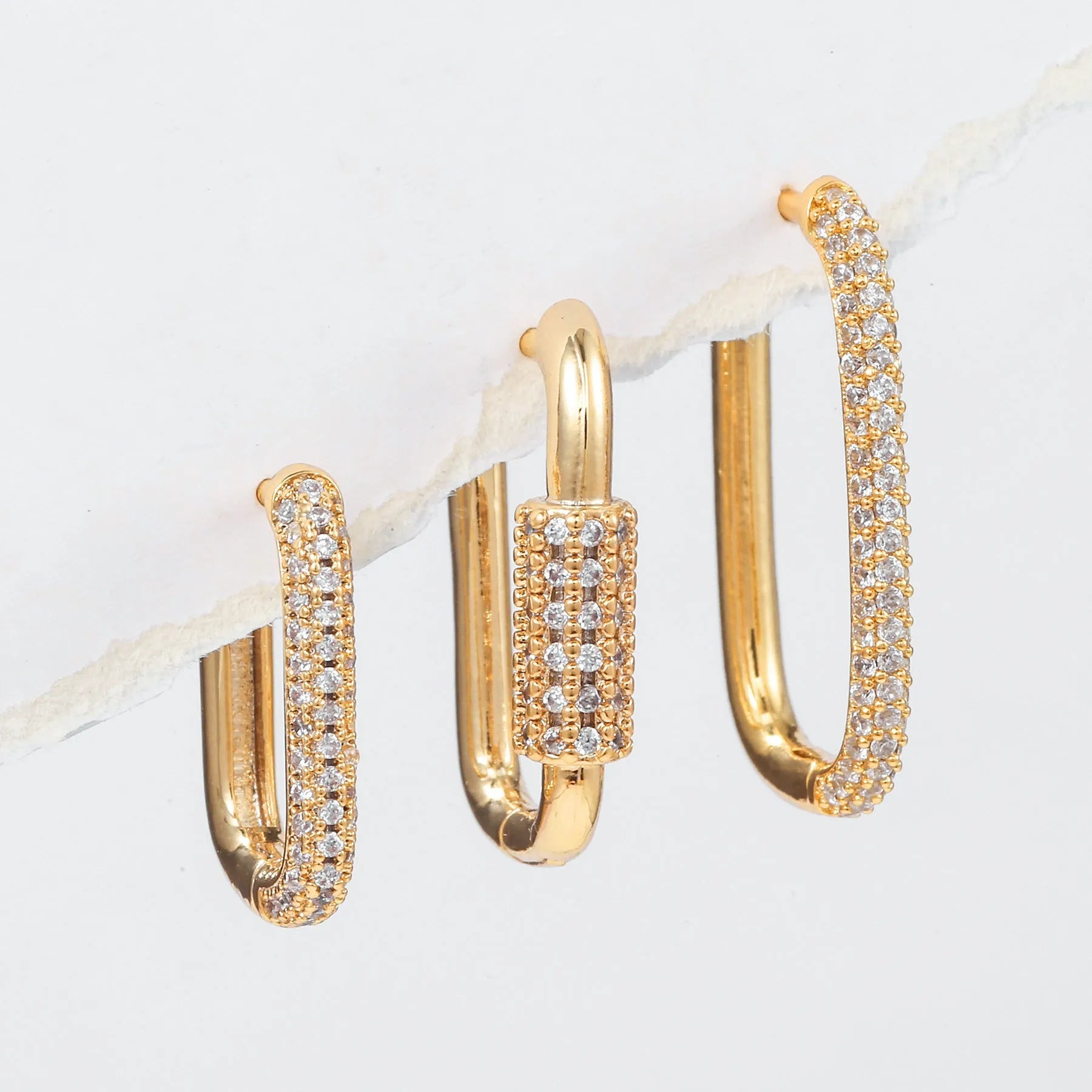 Three geometric copper ear clips with zircon detailing in ellipse and quadrilateral shapes on ear