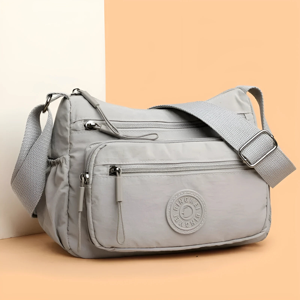Soft water-repellent nylon crossbody bag in grey with a front 3D pocket.