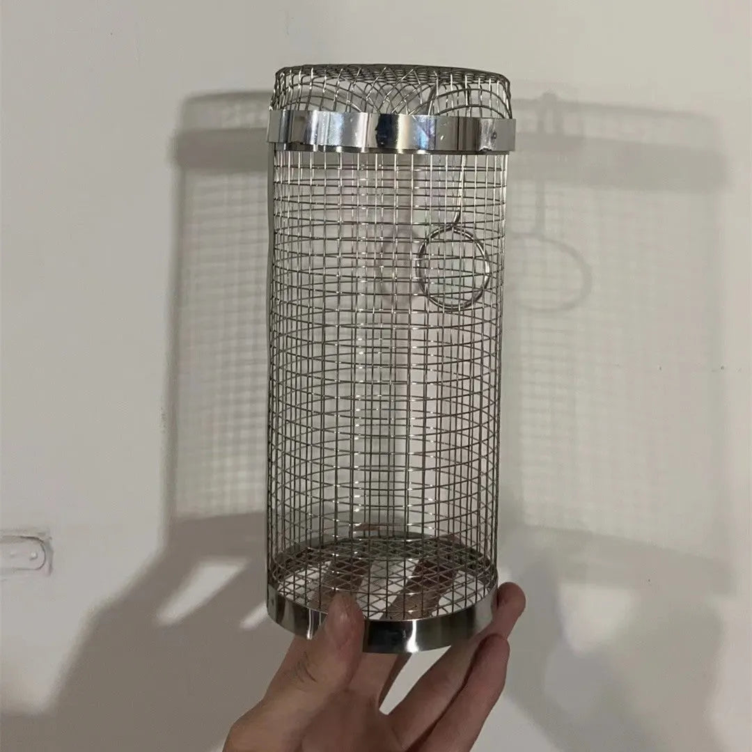 Stainless steel cylindrical rolling grill basket for BBQ with wire mesh, shown with vegetables inside.