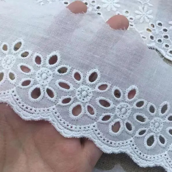 Reel of white embroidered cotton lace trim with a cutout design, showing four different width styles for DIY sewing.