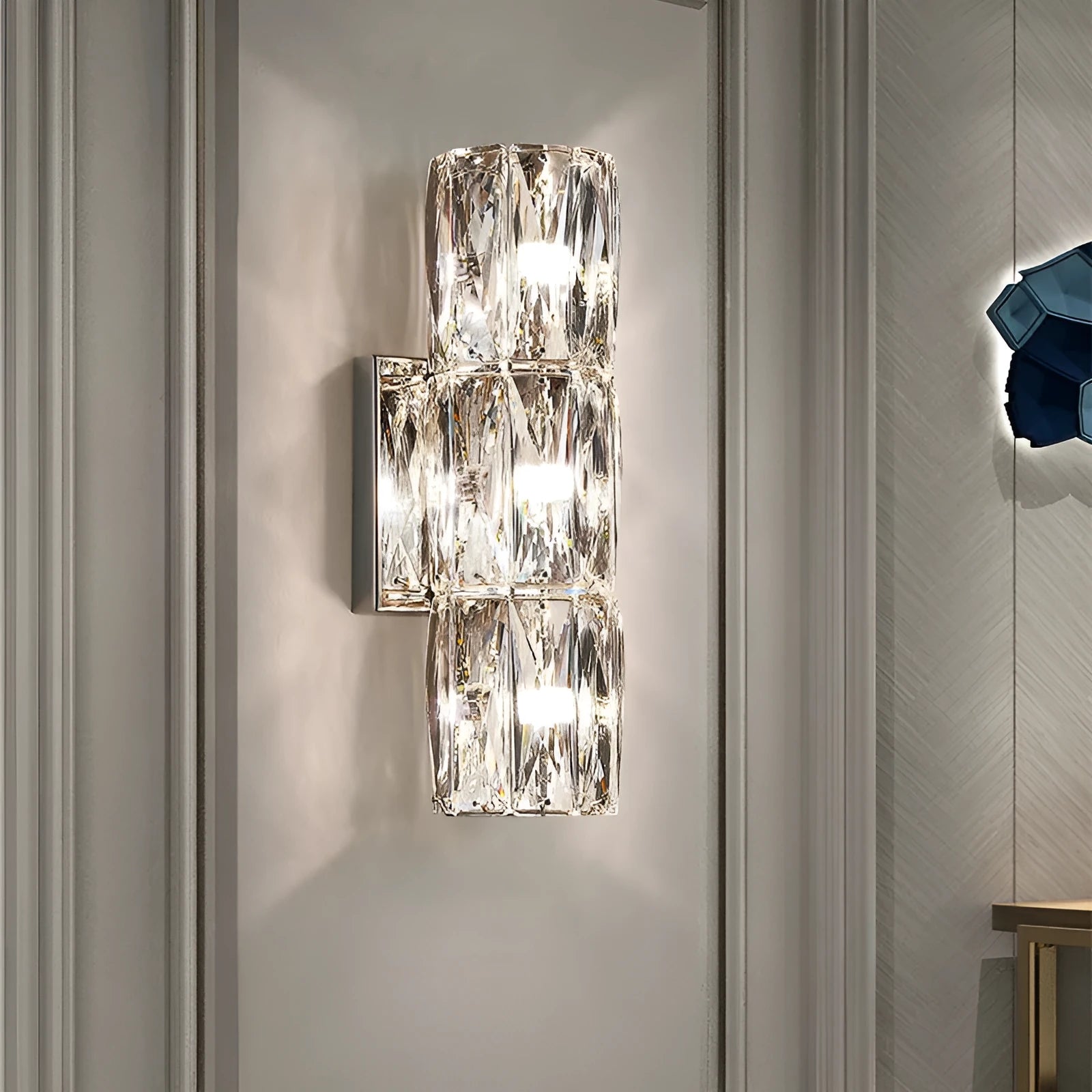 A sleek crystal wall lamp with a stainless steel base in chrome finish, mounted on a wall.