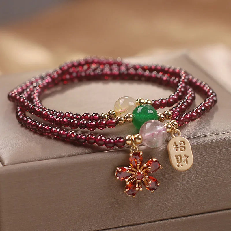 Women's crystal bracelet with pomegranate red cherry blossom beads and sequin details on a simple band.