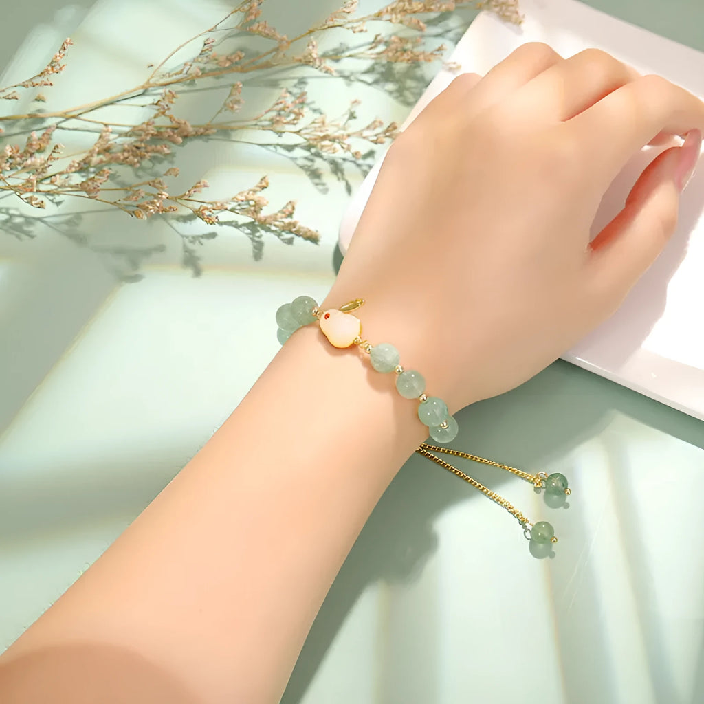 Women's rabbit charm bracelet with green aventurine and strawberry quartz beads, copper and gold details.