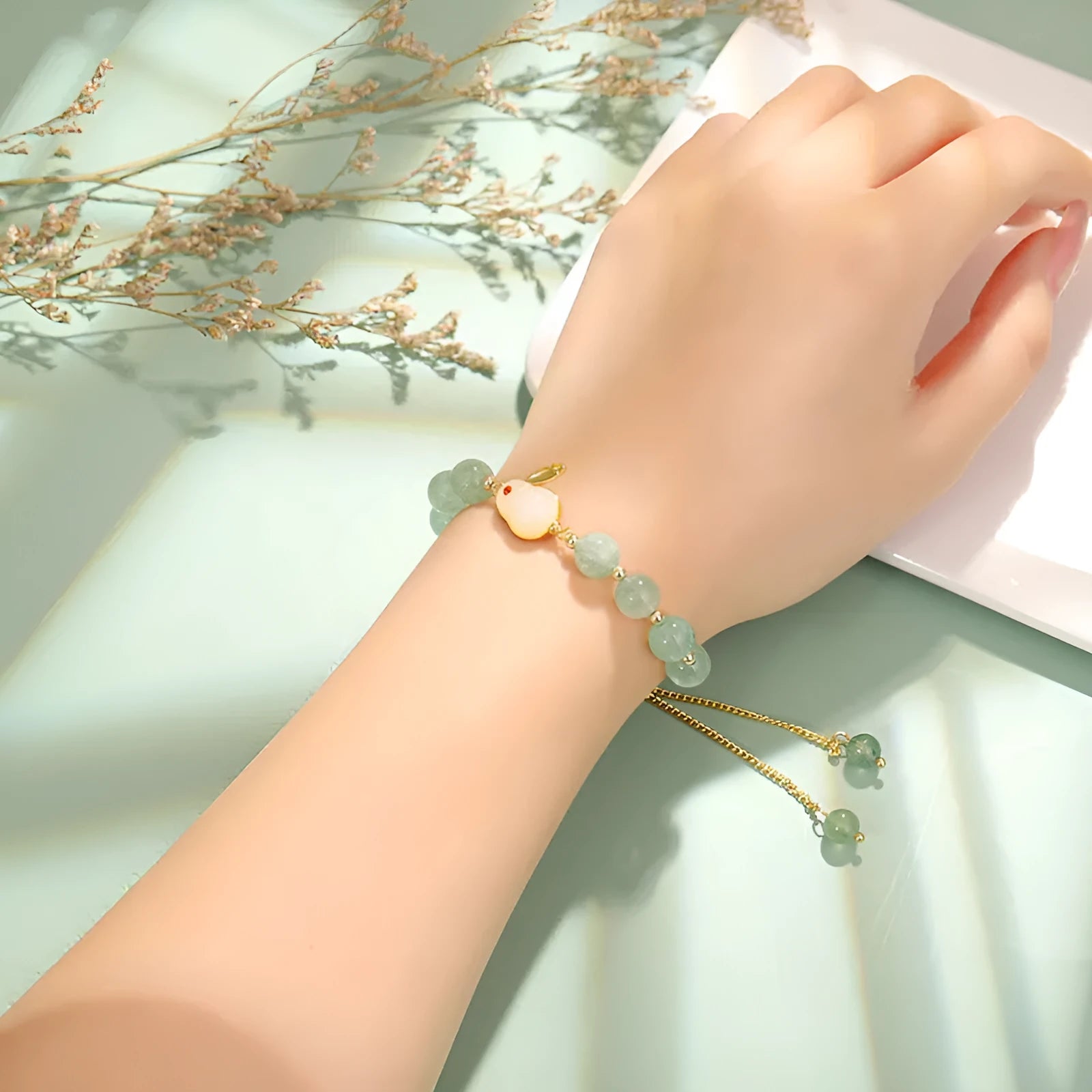 Women's rabbit charm bracelet with green aventurine and strawberry quartz beads, copper and gold details.