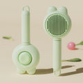 Cat grooming brush with green handle, self-cleaning button, and stainless steel comb for pet hair removal