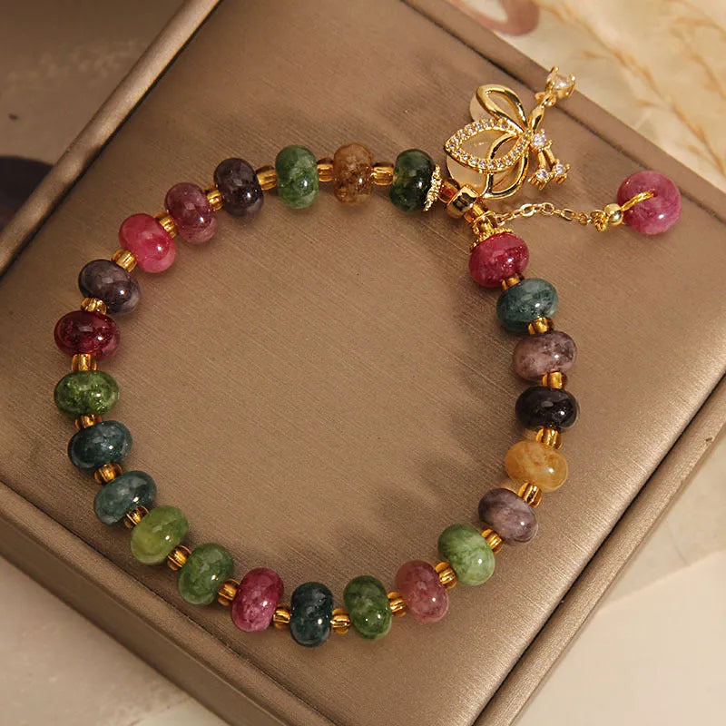 Colourful women's alloy bracelet with multicoloured beads and a butterfly charm on a wrist.