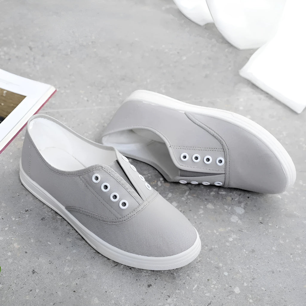 Low-top canvas sneakers in black, white, grey, and pink with a flat heel and cloth lining.