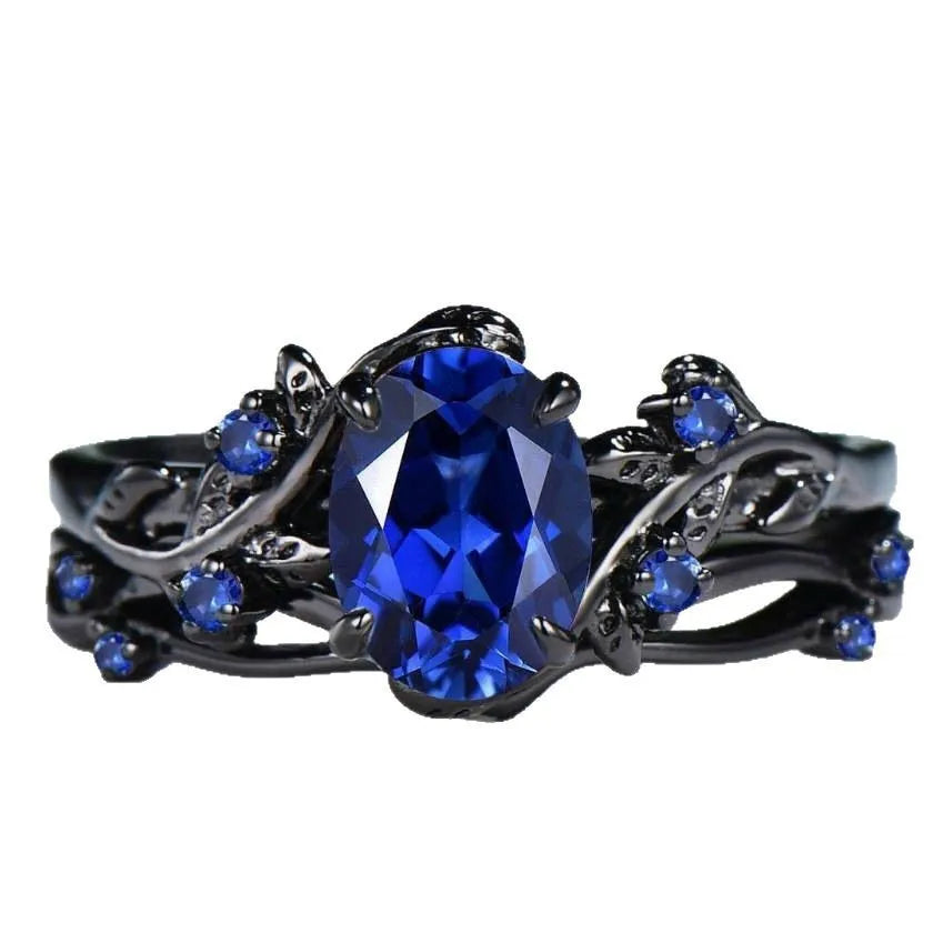 Gun black and navy blue rhinestone geometric couple ring for women on a plain background.