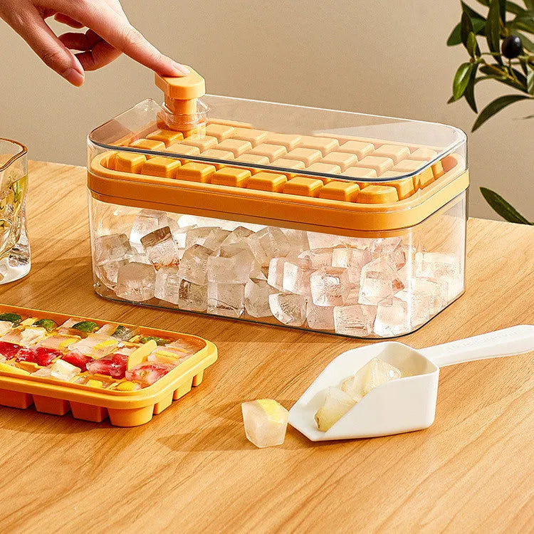 Green one-button press ice cube mould with transparent lid and ice shovel on a kitchen counter