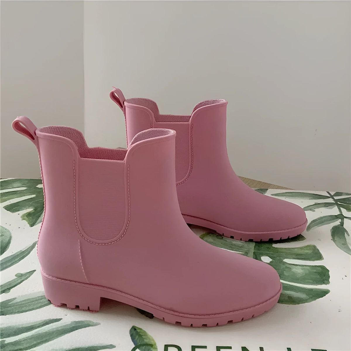 Pair of short rain boots in pink, milky white, or black with non-slip sole and mid-calf length
