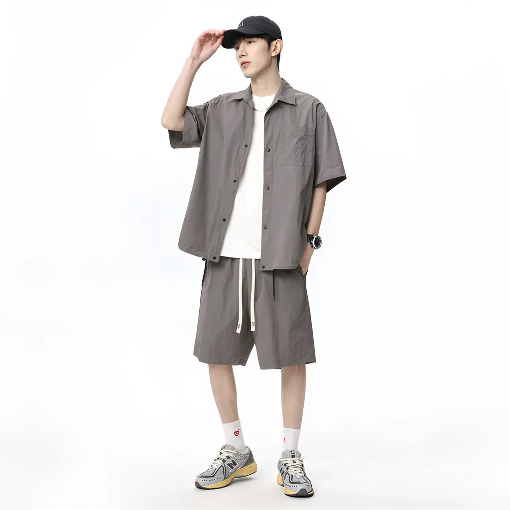 Man wearing a dark grey shirt and matching loose shorts from a men's casual two-piece set.