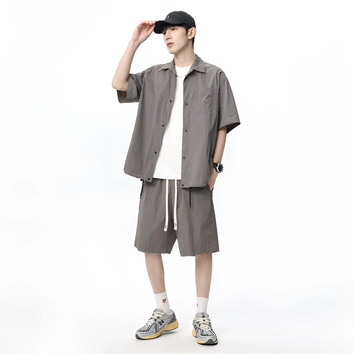 Man wearing a dark grey shirt and matching loose shorts from a men's casual two-piece set.