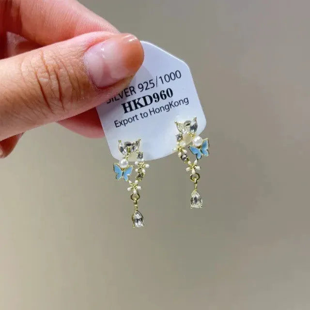 Geometric gold-tone clip-on earrings with a dangling tassel, rhinestone stars, and a heart charm.