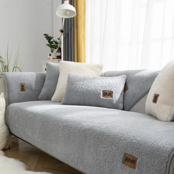 Lambswool sofa cover in blue colour on a grey sofa, showing simple solid colour design