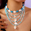 Blue and multi-colour women's multi-layer necklace set with shell, conch, and starfish bead pendants on a white background.