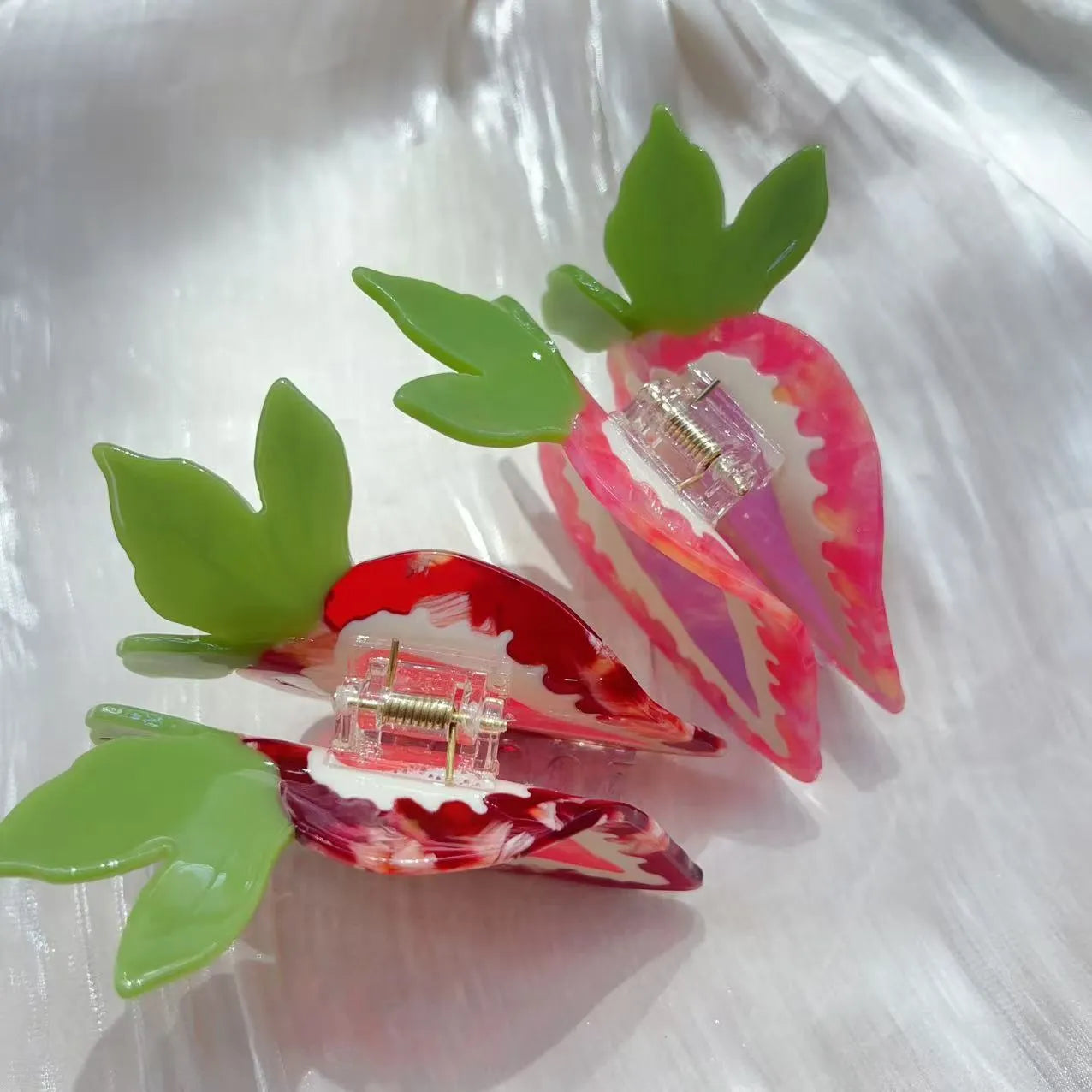Handmade red strawberry hairpin with pastoral style design on a pink background