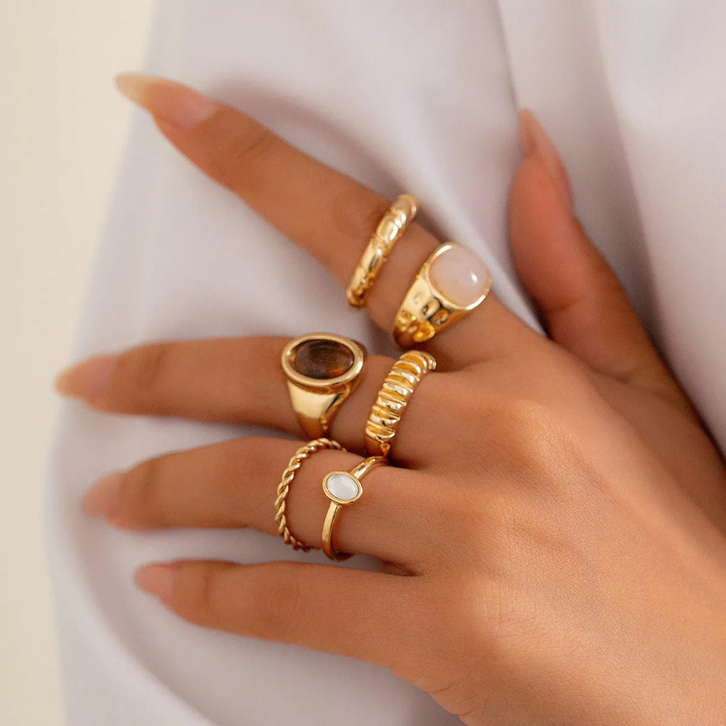 Six irregular geometric alloy rings in light gold colour arranged for display