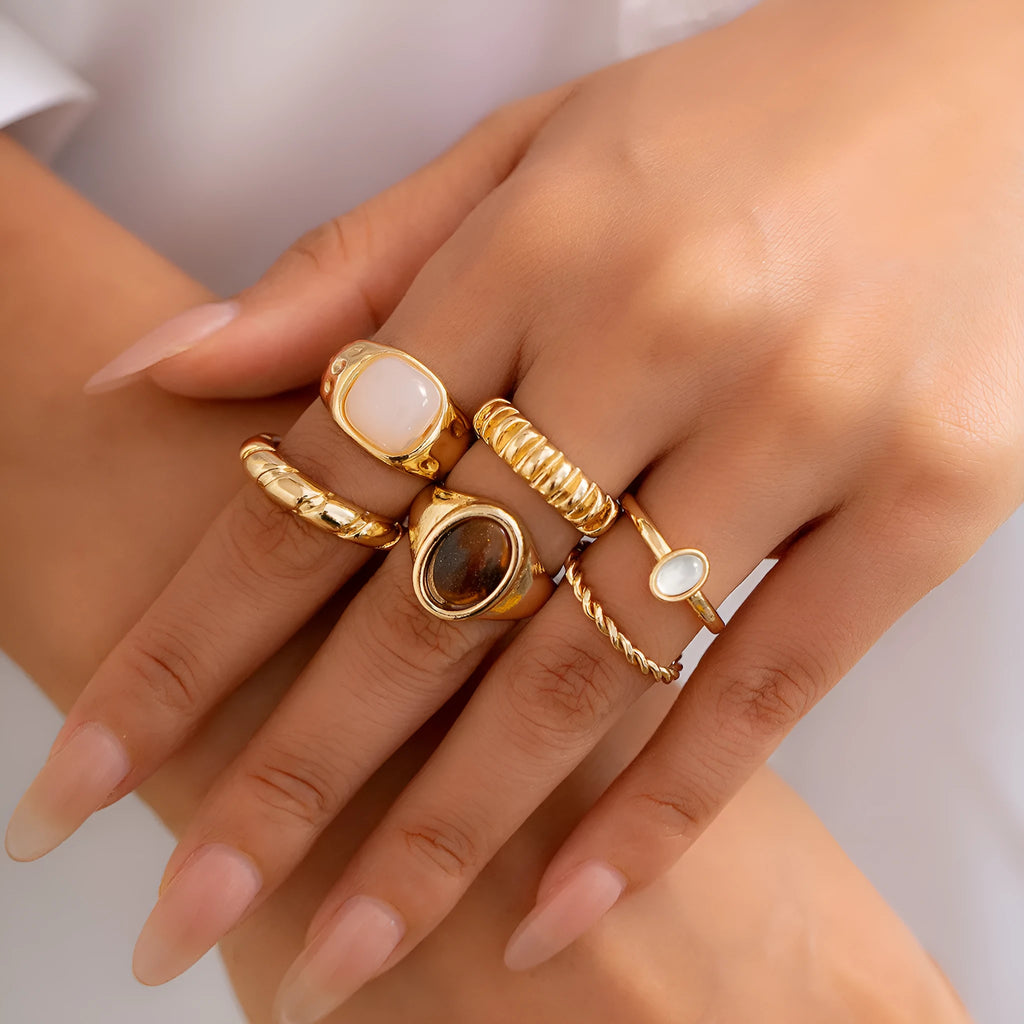 Six irregular geometric alloy rings in light gold colour arranged for display