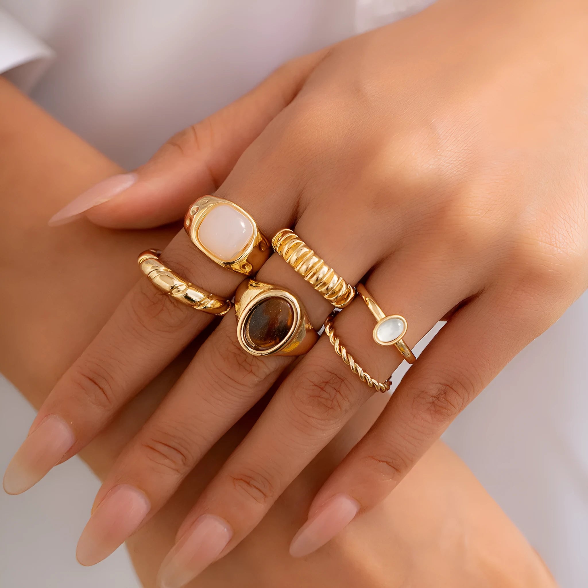 Six irregular geometric alloy rings in light gold colour arranged for display