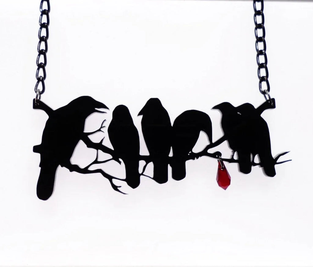 Black crow pendant necklace with cross chain on dark background