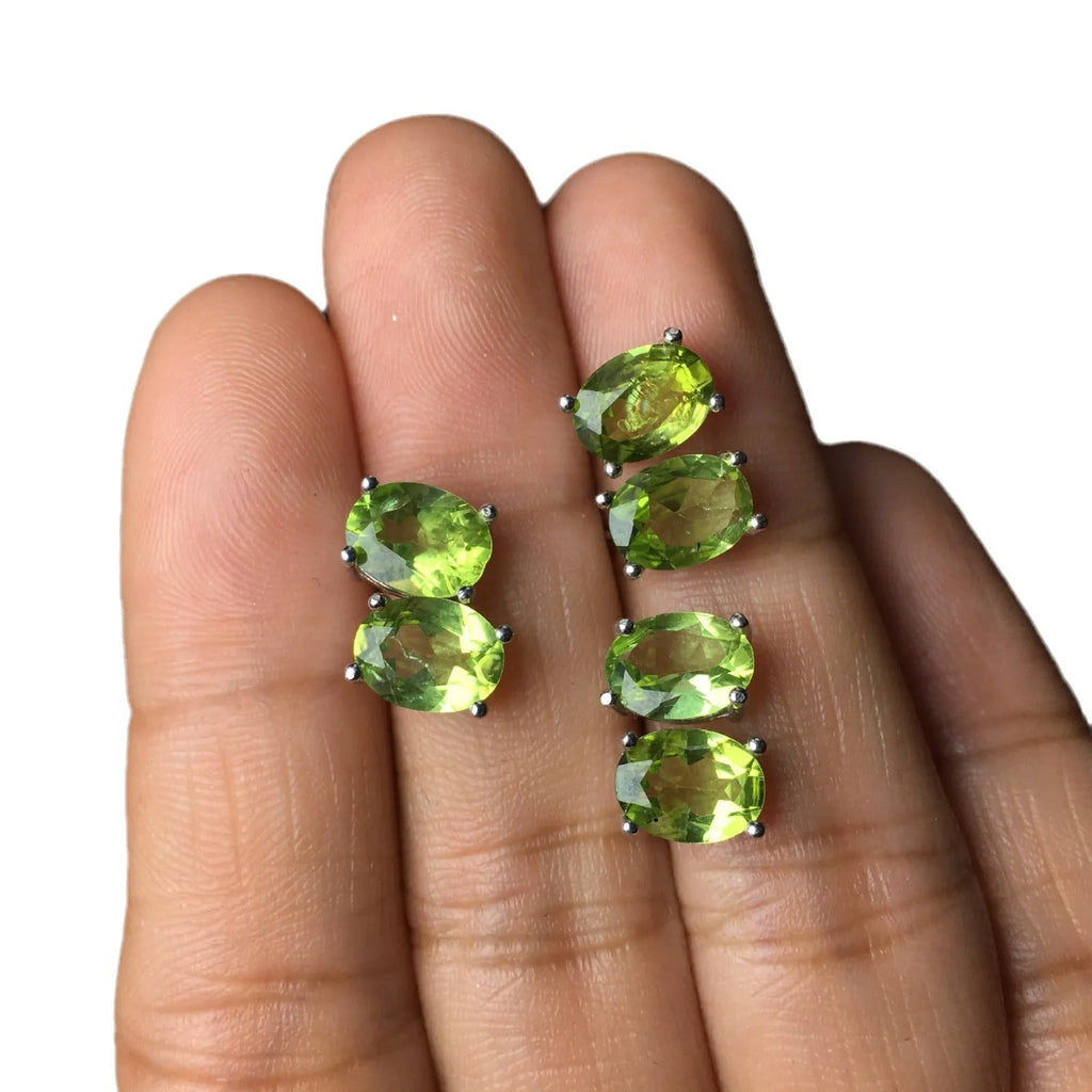 Close-up of grass green olivine stud earrings with elliptical 6x8mm stones in sterling silver setting.