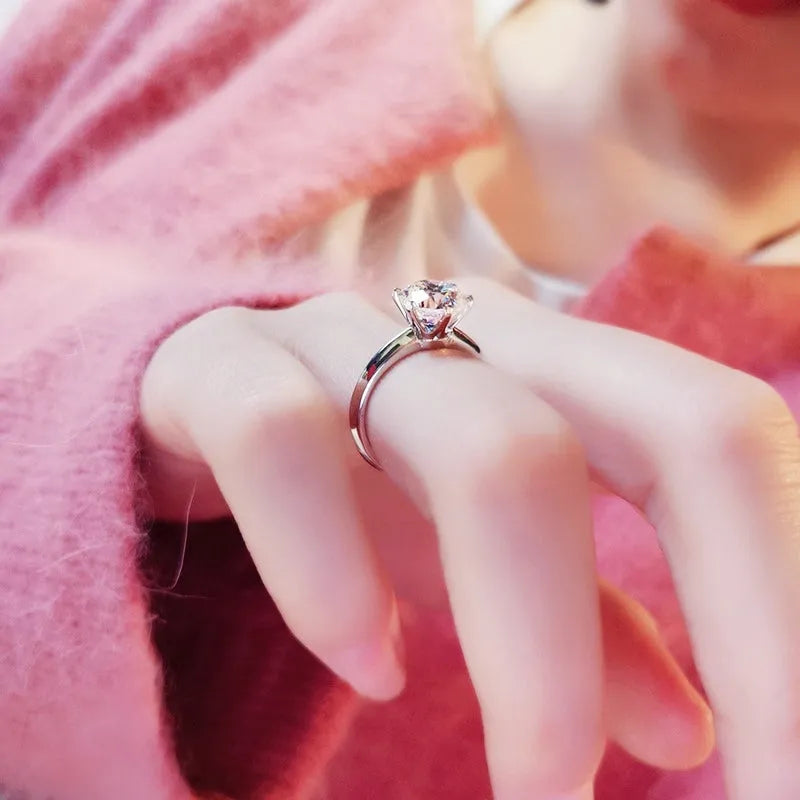 White gold plated six-claw zircon ring with a geometric design on a finger.