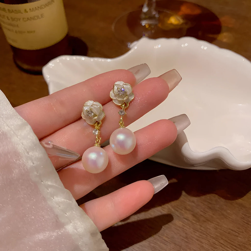 Close-up of camellia flower-shaped stud earrings for women in a pearl-like finish.